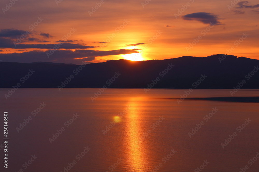 Beautiful sunset on the lake. The sun is leaving the mountains. Background. Landscape.