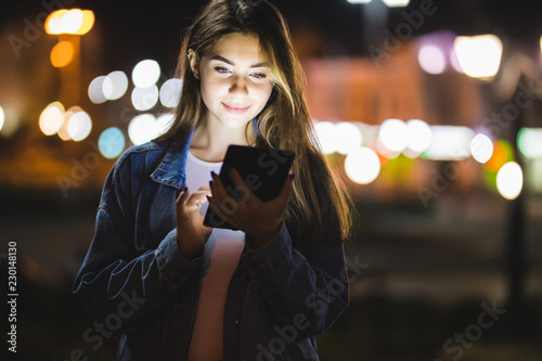 Beautiful young woman using tablet in the city at night bokeh