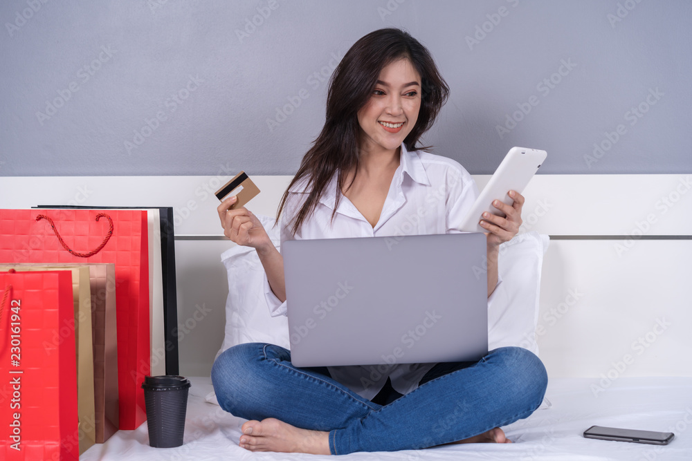 happy woman using tablet for online shopping with credit card on bed happy woman using tablet for online shopping with credit card on bed
