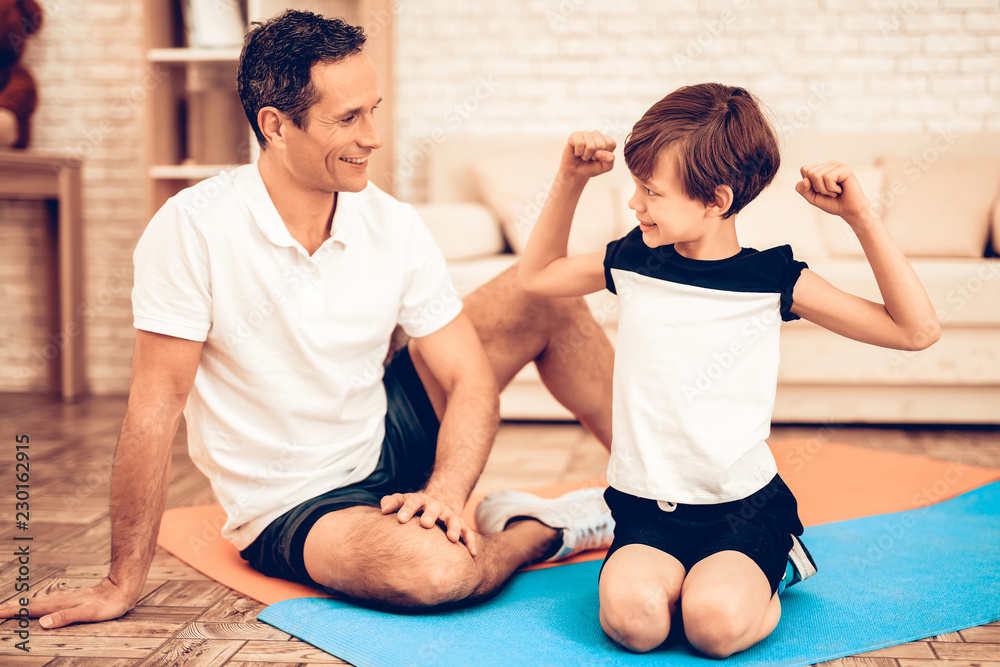 Boy Sitting on Floor Showing Man Muscles at Home. Boy Sitting on Floor Showing Man Muscles at Home.