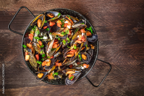 Skillet of marinara mussels on rustic background with copyspace