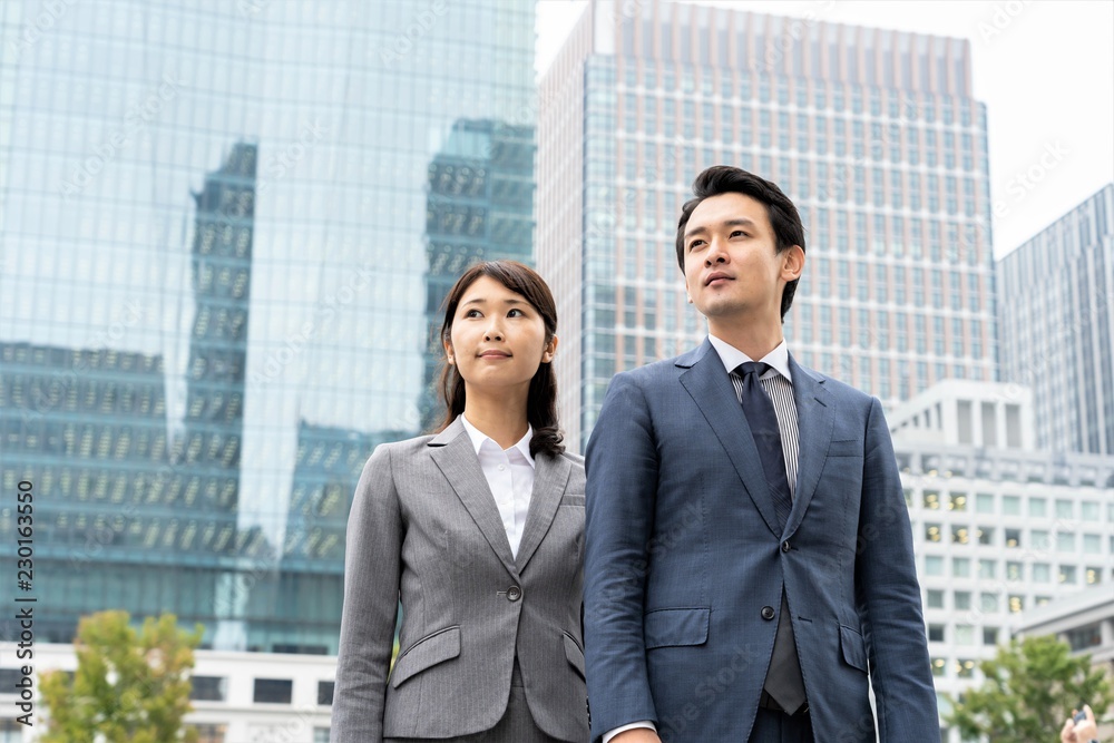 ビルをバックに外を眺める二人のビジネスマン