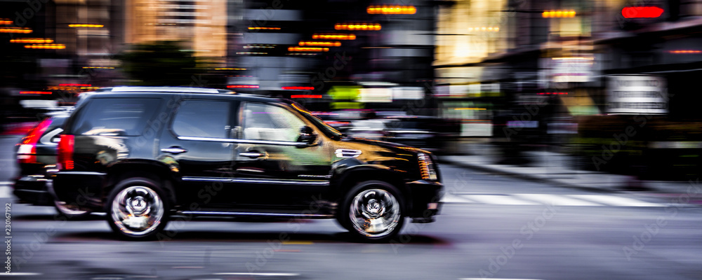 Black SUV speeding down a road in downtown Chicago - obrazy, fototapety, plakaty 