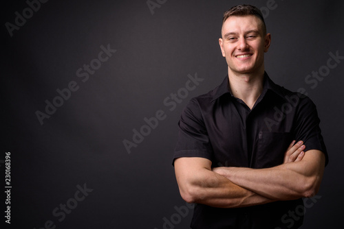 Portrait of young confident businessman smiling with arms crossed looking at camera