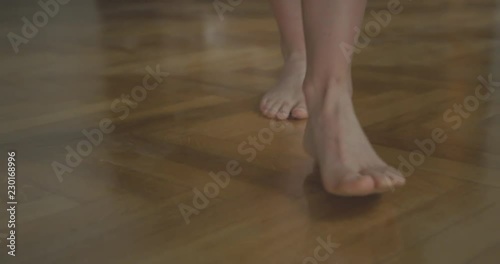 Bare feet of a young woman walking on a parquet floor