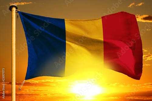 Obraz na plátně Romania flag weaving on the beautiful orange sunset with clouds background