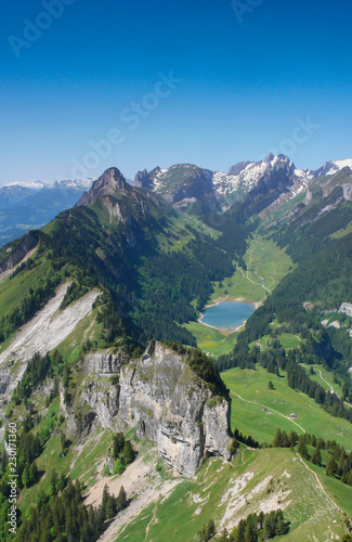mountain landcape in the Alpstein region of Switzerland with jagged peaks and a pristine blue mountain lake in the valley far below