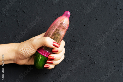 Unknown woman holds a cucumber and condom