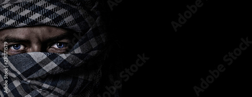 an arab face in a scarf keffiyeh on a black background photo