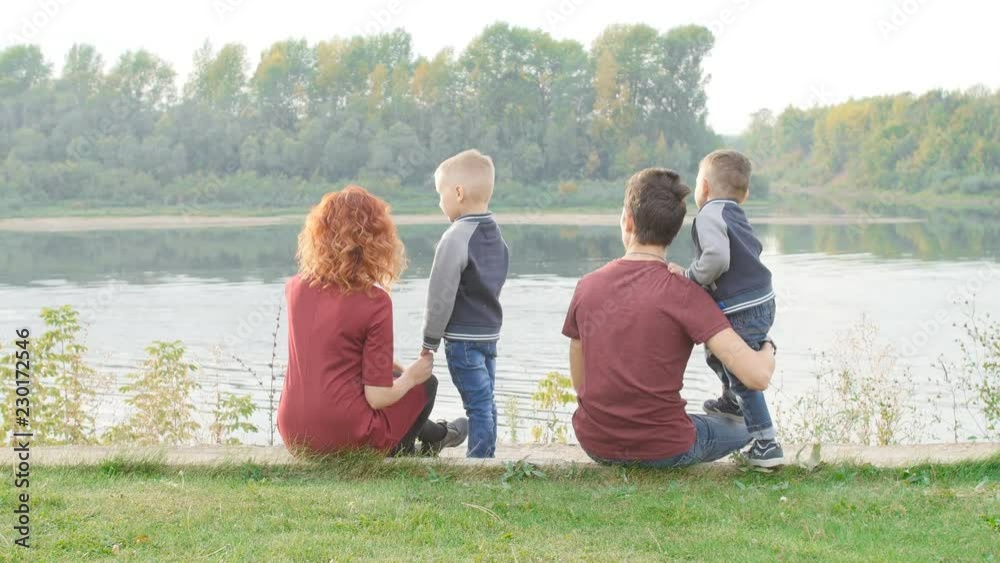 Family and children concept. Young couple with two sons walking by the river Family and children concept. Young couple with two sons walking by the river
