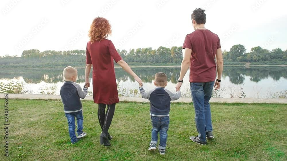 Family and children concept. Young couple with two sons walking by the river Family and children concept. Young couple with two sons walking by the river