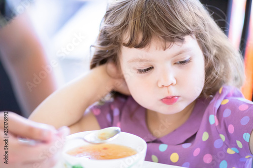 Cute little girl doesn't want to eat. Kid refusing food. Sad child