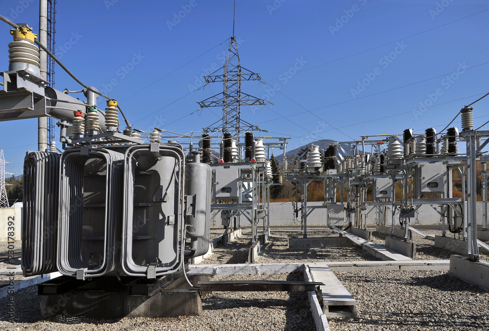 High voltage oil-filled power transformer on electrical substation.Part of  high-voltage substation with switches and dis connectors on blue sky  background Stock-Foto