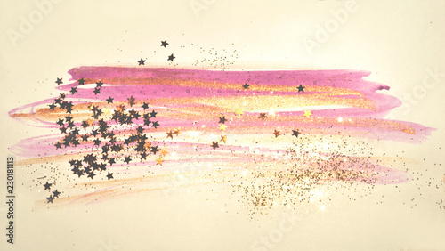 Golden glitter and glittering stars on abstract pink and gold watercolor splashes in vintage nostalgic colors.