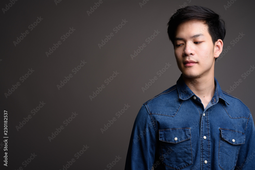 Fototapeta premium Young handsome Asian man wearing denim shirt