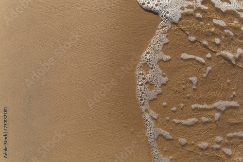 Fototapeta Naklejka Na Ścianę i Meble -  Beautiful sunlit small waves foam of shallow clear water on the smooth sand 