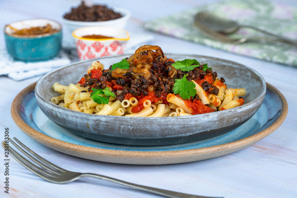 Kushari - Egyptian vegetarian dish with lentils, spiced tomato sauce and macaroni topped with fried onions Kushari - Egyptian vegetarian dish with lentils, spiced tomato sauce and macaroni topped with fried onions