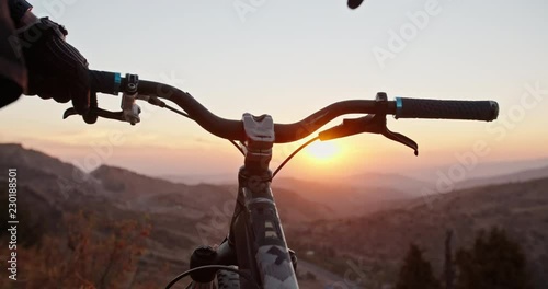 Mountain biker putting his hands on bicycle wheel, ready to go down the mountain in sunset - gettng away from it all, activity, extreme 4k photo