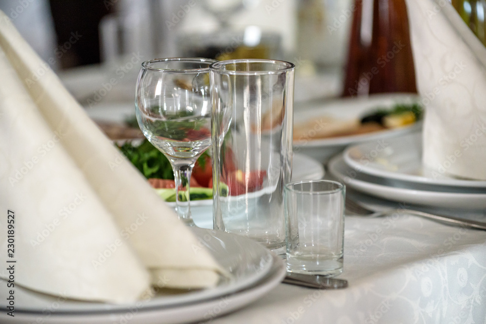 Beautiful table setting with crockery and flowers for a party, wedding reception or other festive event. Glassware and cutlery for catered event dinner
