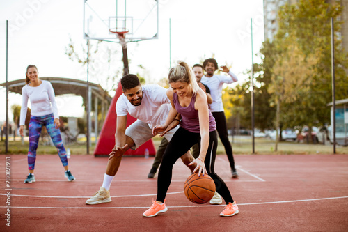 Group of multiracial young people   playing basketball outdoors © BGStock72