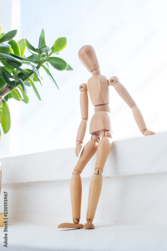 A wooden mannequin sits thoughtfully at the window. A wooden mannequin sits thoughtfully at the window.