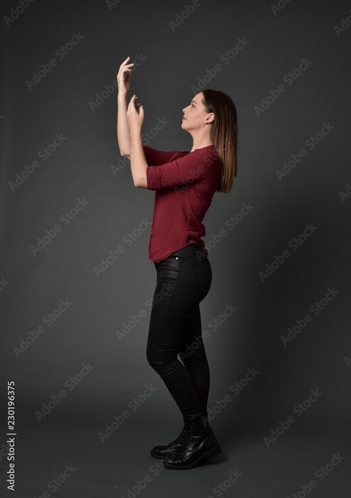full length portrait of brunette girl wearing red shirt and leather pants. standing pose , on grey studio background. full length portrait of brunette girl wearing red shirt and leather pants. standing pose , on grey studio background.