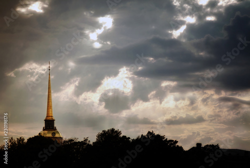 The gilded spire of the Admiralty in St. Petersburg against the sky with thunderclouds