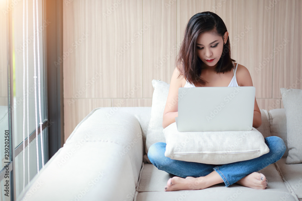 beautyful woman portrait using computer with white vest and blue jean in living room on relax day beautyful woman portrait using computer with white vest and blue jean in living room on relax day