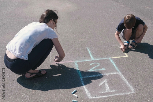 Mother and son drawing together hopscotch on the pavement. photo