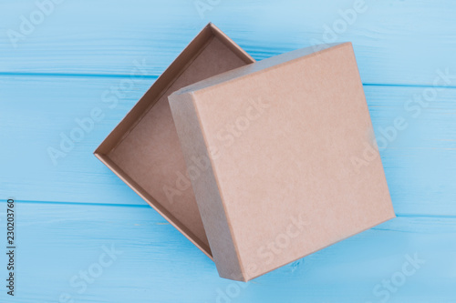 Cardboard craft box, top view. Top view of brown box. Blue wood background.