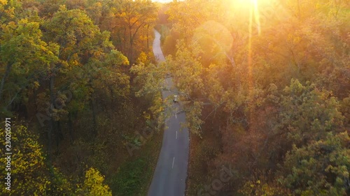 Aerial view on car driving through autumn forest road. Scenic autumn landscape photo