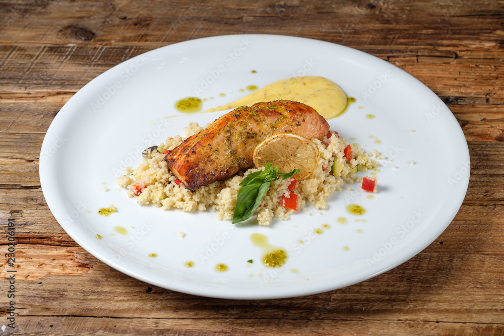 Baked salmon slice with couscous on a white plate
