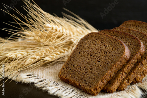 Sliced rye bread on black background with ears.