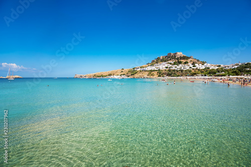 View of sandy beach in Bay of Lindos, Acropolis in background (Rhodes, Greece).