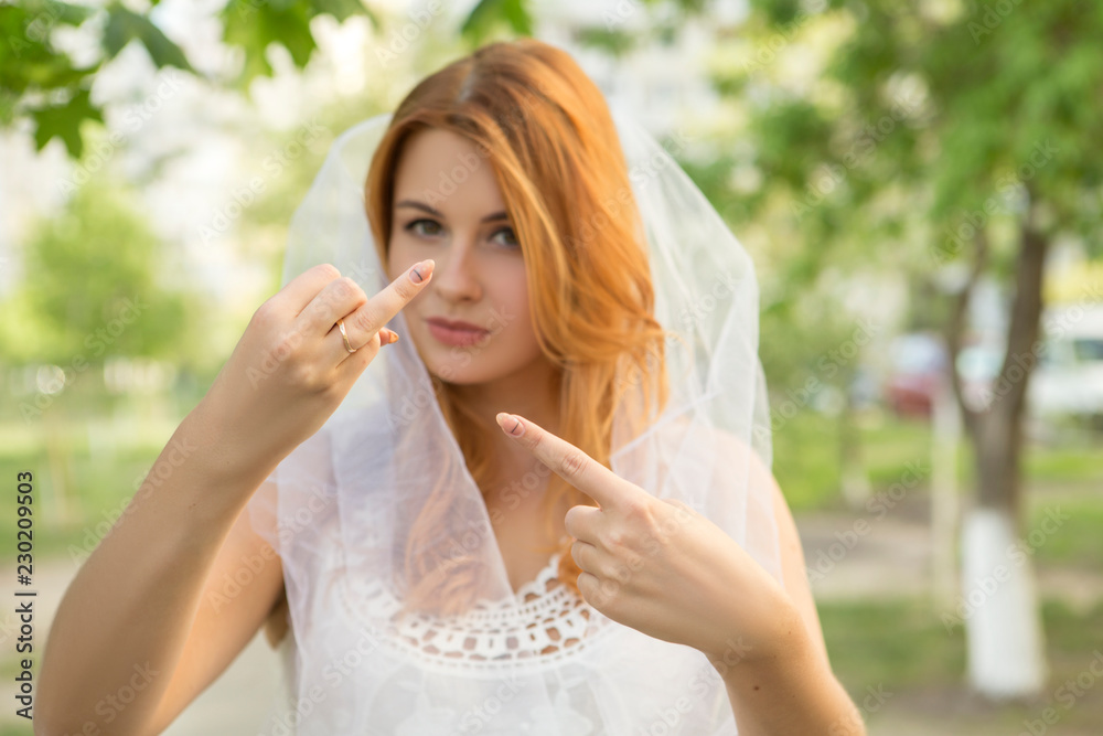 Sexy brunette caucasian woman in white wedding veil and dress. She pointing on her ring finger, shocked troubled expression on her face. Copy space