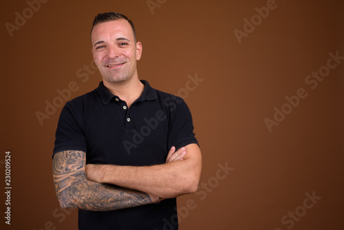 Man wearing black shirt against brown background