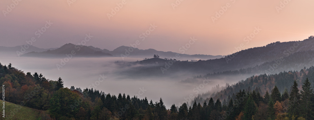 Fototapeta premium Panoramiczny mglisty krajobraz o świcie nad górami i doliną