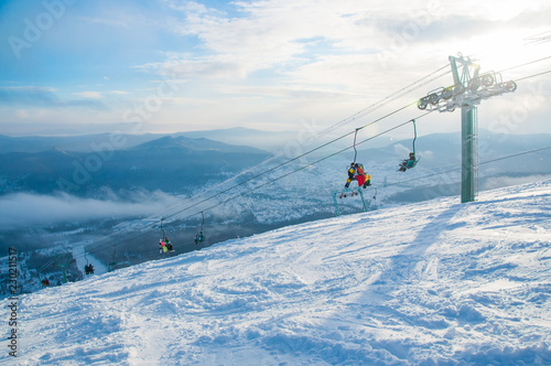 Ski lift with snowboarders and skiers. Blue sky and sun. Sheregesh ski resort. Sheregesh is one of the most famous ski resorts of Russia. Mountain Shoria. Winter holiday.