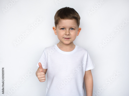 little cute boy in a white t-shirt showing thumbs up, ok sign