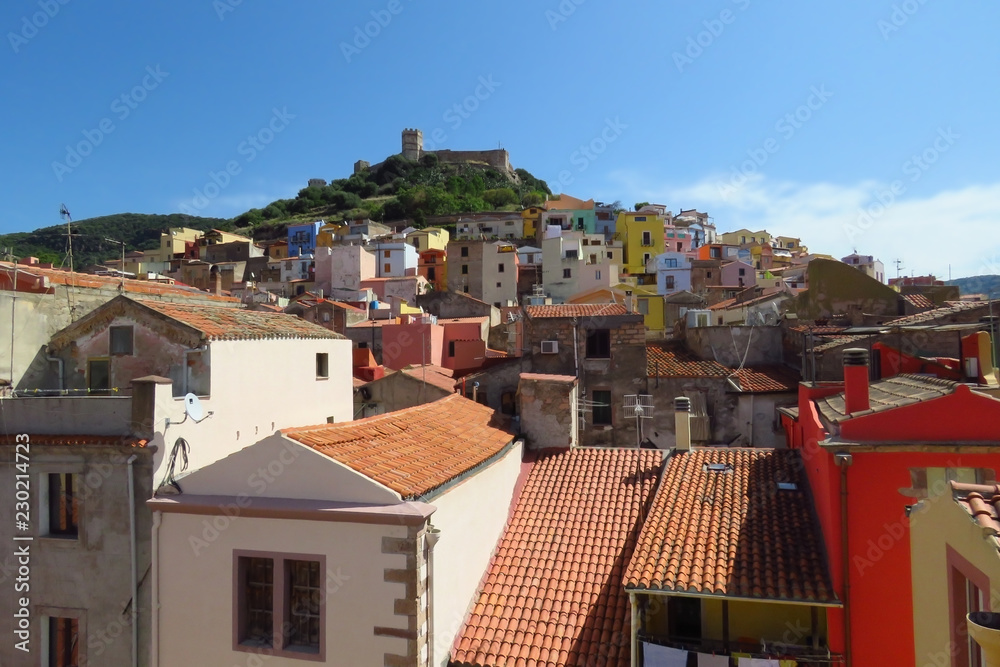 Colourful houses in the medieval town of Bosa with the castle of Serravalle towering over the red rooftops, Sardinia, Italy