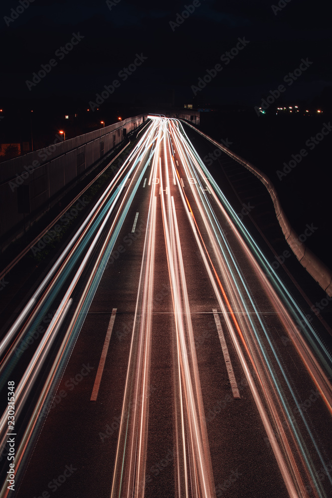 White light trails from cars on a traffic motorway at night view. Abstract motion blur movement
