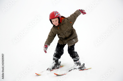 Young student boy practices ski sport moves. White snow background.