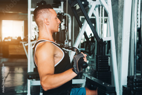 Man flexing muscles on cable machine in gym