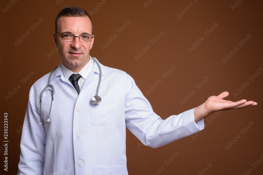Man doctor wearing eyeglasses against brown background Man doctor wearing eyeglasses against brown background