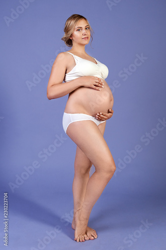 Beautiful pregnant woman in lingerie posing over lilac background.   © reggeyreggey