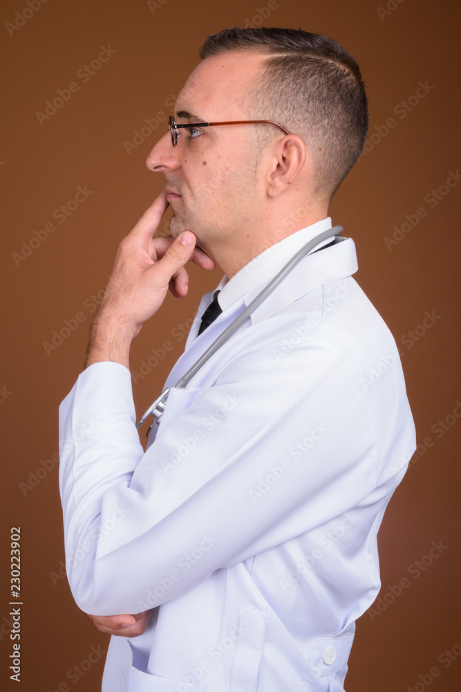 Man doctor wearing eyeglasses against brown background Man doctor wearing eyeglasses against brown background