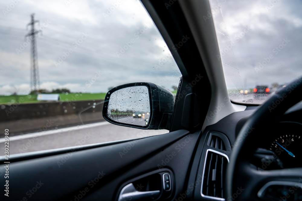 Vehicle interior with a view into the rearview mirror where headlight is reflected in the rain