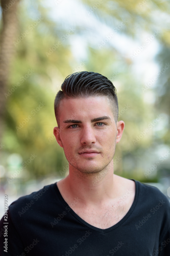Portrait of young handsome man looking at camera outdoors Portrait of young handsome man looking at camera outdoors