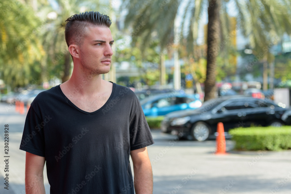 Young handsome man standing while thinking in the parking lot