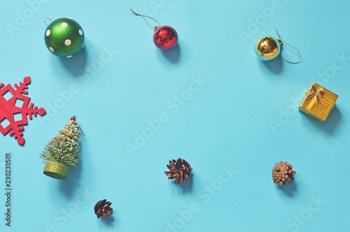 Flat lay Christmas photography. Snowflake, colorful balls, golden gift box, decorative fir tree and pine cones on a blue background. New Year home decoration
